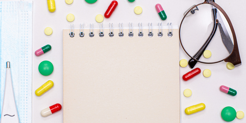 Medical concept. Multicolored pills, Notepad, thermometer, glasses white background.